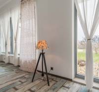 I PREDAJ moderná vila s bazénom a veľkým pozemkom - Interiér Vily s podlahou s dreveným dekorom, veľkými oknami a stojacou lampou.