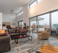 I PREDAJ moderná vila s bazénom a veľkým pozemkom - Priestranný interiér vily s veľkými oknami a pohodlným nábytkom, podlaha s dreveným dekorom.