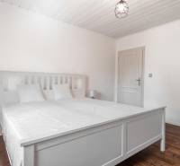 Stavebný pozemok 8 500 m² s podnikateľským potenciálom - Biela spálňa s manželskou posteľou a podlahou s dreveným dekorom.