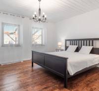 Stavebný pozemok 8 500 m² s podnikateľským potenciálom - Spálňa s posteľou, podlahu zdobí drevený dekor, svetelný luster, záclony na oknách.
