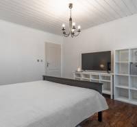 Stavebný pozemok 8 500 m² s podnikateľským potenciálom - Spálňa s lusterom, TV, regálmi a podlahou s dreveným dekorom. Pozemky - bývanie.