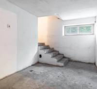 I Na predaj dvojposchodový 5i rodinný dom pri Žiline - Betónové schody vedú do pivnice v rodinnom dome, s malým oknom a bielymi stenami.