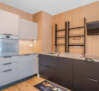 : Nadštandardný 2-i byt v projekte ZWIRN za cenu „štandardu“ - Kuchyňa v 2-izbovom byte s drevenými prvkami, vstavanou rúrou a sivými skrinkami.