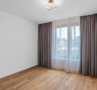 : Nadštandardný 2-i byt v projekte ZWIRN za cenu „štandardu“ - Izba s drevenou podlahou a veľkým oknom so závesmi v 2-izbovom byte.