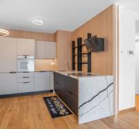 : Nadštandardný 2-i byt v projekte ZWIRN za cenu „štandardu“ - Kuchyňa v 2-izbovom byte s drevenou podlahou a modernými spotrebičmi.