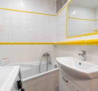 Exkluzívny byt v srdci Vysokých Tatier na Štrbskom Plese - Kúpeľňa Rekreačného apartmánu s vaňou, umývadlom, práčkou a bielymi obkladmi.