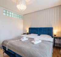 Exkluzívny byt v srdci Vysokých Tatier na Štrbskom Plese - Spálňa v Rekreačnom apartmáne s manželskou posteľou a podlahou s dreveným dekorom.