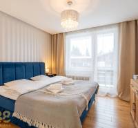 Exkluzívny byt v srdci Vysokých Tatier na Štrbskom Plese - Spálňa v Rekreačnom apartmáne s pohodlnou posteľou a podlahou s dreveným dekorom.