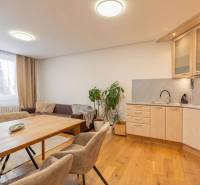 Exkluzívny byt v srdci Vysokých Tatier na Štrbskom Plese - Interiér rekreačného apartmánu s pohovkou, kuchyňou a podlahou s dreveným dekorom.