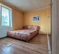 Priestranný 2-izbový byt s potenciálom zmeny dispozície- Šaca - Spálňa v 2-izbovom byte s posteľou, šatníkmi a podlahou s dreveným dekorom.