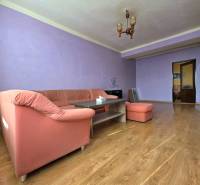 Priestranný 2-izbový byt s potenciálom zmeny dispozície- Šaca - Obývacia izba v 2-izbovom byte s fialovými stenami a podlahou s dreveným dekorom.