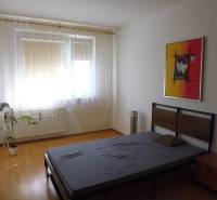 PRENÁJOM: M.NEŠPORA - 2-izbový byt, 58 m2, 7.posch. - Sídlisko III. - Štýlová spálňa v 2-izbovom byte s podlahou s dreveným dekorom a umeleckým obrazom.