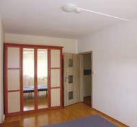 PRENÁJOM: M.NEŠPORA - 2-izbový byt, 58 m2, 7.posch. - Sídlisko III. - Interiér 2-izbového bytu s veľkou zrkadlovou skriňou a podlahou s dreveným dekorom.