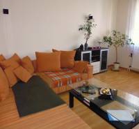 PRENÁJOM: M.NEŠPORA - 2-izbový byt, 58 m2, 7.posch. - Sídlisko III. - Obývacia izba v 2-izbovom byte s oranžovou sedacou súpravou a podlahou s dreveným dekorom.