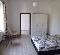 PRENÁJOM: HLAVNÁ - VOĽNÝ 2,5-izbový byt + kuchyňa, kúpeľňa, WC  - Spálňa v 3-izbovom byte s podlahou s dreveným dekorom, skriňou a posteľou.