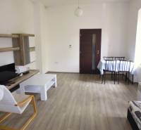 PRENÁJOM: HLAVNÁ - VOĽNÝ 2,5-izbový byt + kuchyňa, kúpeľňa, WC  - Obývacia izba v 3-izbovom byte so svetlým nábytkom a podlahou s dreveným dekorom.