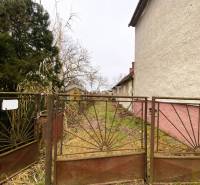 TOP PONUKA !! 3-izb. RD, INVESTÍCIA, Borský Svätý Jur - Starý plot bráni vstupe do zarasteného pozemku**.** Rodinný dom s bielou fasádou na boku.