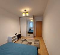 4-izb. byt na ul. Wolkrova, Petržalka, upravený na 2 bytové jednotky - Spálňa so vstavanou skriňou, posteľou a podlahou s dreveným dekorom v 4-izbovom byte.