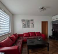 4-izb. byt na ul. Wolkrova, Petržalka, upravený na 2 bytové jednotky - Obývacia izba so sedačkou, stolíkom a podlahou s dreveným dekorom v 4-izbovom byte.