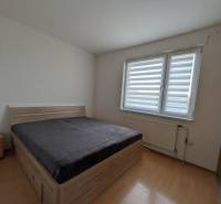 4-izb. byt na ul. Wolkrova, Petržalka, upravený na 2 bytové jednotky - Spálňa so svetlým nábytkom, posteľou a podlahou s dreveným dekorom v 4-izbovom byte.