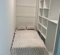 Novostavba 2,5-izb. bytu v NUPPU, garážové státie + vonkajšie státie - Úzka spálňa v 2-izbovom byte s posteľou a otvorenými policami.