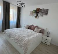 Novostavba 2,5-izb. bytu v NUPPU, garážové státie + vonkajšie státie - Spálňa 2-izbového bytu so svetlou podlahou s dreveným dekorom a moderným osvetlením.