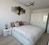 Novostavba 2,5-izb. bytu v NUPPU, garážové státie + vonkajšie státie - Spálňa v 2-izbovom byte s posteľou, skriňou a podlahou s dreveným dekorom.