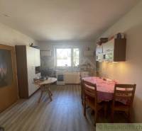 Trojizbový rodinný dom vhodný aj na chalupu v kľudnej časti obce Jatov - Kuchyňa v rodinnom dome s dreveným dekorom podlahy, jednoduchý nábytok a jedálenský stôl.