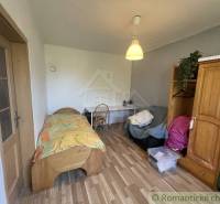 Trojizbový rodinný dom vhodný aj na chalupu v kľudnej časti obce Jatov - Izba v rodinnom dome s posteľou, stolom a podlahou s dreveným dekorom.