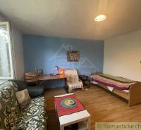 Trojizbový rodinný dom vhodný aj na chalupu v kľudnej časti obce Jatov - Izba v rodinnom dome s posteľou, oknom, sedačkou a podlahou s dreveným dekorom.