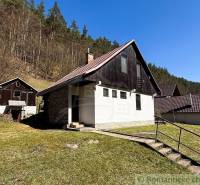 Chalupa - rodinný dom v krásnom prostredí – Moštenica, Banská Bystrica - Chata v Moštenici, obklopená prírodou a lesom, s jasnou oblohou a trávnatým pozemkom.