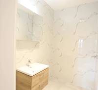 1-izb. byt v novostavbe v Ružinove, 4p./10 - Kúpeľňa 1-izbového bytu s dreveným umývadlovým kabinetom a mramorovými stenami.