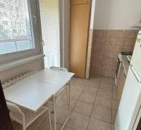 1-izb. byt, J.Stanislava, Karlova Ves, lodžia, 3.p./8 - Svetlá kuchyňa s oknom, jednoduchým stolom a stoličkami v 1-izbovom byte.