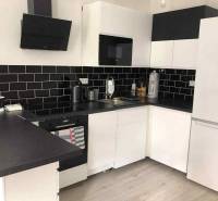 1,5 izb. byt s predzáhradkou, Podunajské Biskupice, projekt Oppidum - Biela kuchyňa s čiernymi obkladmi a podlahou s dreveným dekorom v 2-izbovom byte.