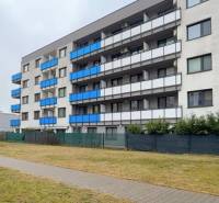 1,5 izb. byt s predzáhradkou, Podunajské Biskupice, projekt Oppidum - Exteriér bytového domu v Bratislave - Podunajské Biskupice s modrými balkónmi a zeleným trávnikom.