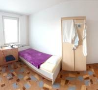 2-izb. byt pri Račianskom Mýte, balkón, 5.p./11 - Spálňa v 2-izbovom byte s posteľou, skriňou a kobercom.