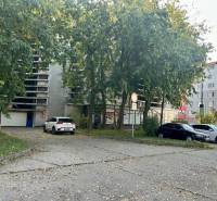Nadštandardne veľká garáž na ul. Medveďovej, Petržalka - Parkovisko pri garážach na Medveďovej v Bratislave-Petržalke, s autami a stromami.