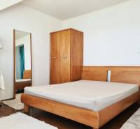 5-izb. dvojpodlažný rodinný dom, Rovinka - Spálňa v rodinnom dome s drevenou posteľou, skriňou, zrkadlom a stojacou lampou.