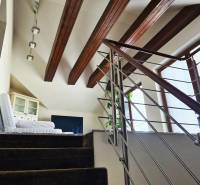 5-izb. dvojpodlažný rodinný dom, Rovinka - Interiér rodinného domu s modernými schodmi, drevenými trámami a kreslom pri okne.