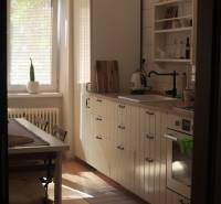 Veľký 2-izb. byt v tehlovom dome, Ružová dolina, Ružinov časť Nivy - Kuchyňa s jedálenským stolom, bielymi skrinkami a podlahou s dreveným dekorom v 2-izbovom byte.