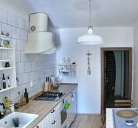 Veľký 2-izb. byt v tehlovom dome, Ružová dolina, Ružinov časť Nivy - Kuchyňa v 2-izbovom byte s podlahou s dreveným dekorom a bielymi skrinkami.