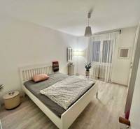 Veľký 2-izb. byt v tehlovom dome, Ružová dolina, Ružinov časť Nivy - Spálňa v 2-izbovom byte s posteľou a podlahou s dreveným dekorom.