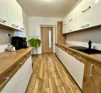 Na predaj: Priestranný rodinný dom v tichej lokalite obce Červeník - Kuchyňa v rodinnom dome s bielymi skrinkami a podlahou s dreveným dekorom.
