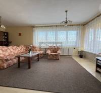 Predaj, rodinný dom Oslany - EXKLUZÍVNE HALO REALITY - Obývačka s kobercom, kvetovanou sedačkou a podlahou s dreveným dekorom v rodinnom dome.