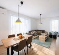 EXKLUZÍVNY 3-IZBOVÝ BYT V SÚKROMNOM KOMPLEXE |2x PARKING | NA PIESKU,  - Obývacia izba s podlahou s dreveným dekorom, jedálenským stolom a pohodlnou sedačkou.