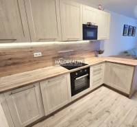 Predaj, dvojizbový byt Bratislava Podunajské Biskupi... - Kuchyňa s podlahou s dreveným dekorom v 2-izbovom byte, svetlé drevené skrinky a vstavané spotrebiče.