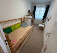 4 Izbový byt na Kríkovej ulici na predaj - Detská izba v 4-izbovom byte s posteľou, komodou a farebnými závesmi.