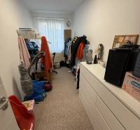 4 Izbový byt na Kríkovej ulici na predaj - Úzka miestnosť v 4-izbovom byte s komodou, regálmi a oknom bez závesov.