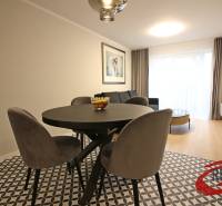 **SKVELÁ INVESTÍCIA**REZIDENCIA OPERA**KÚPELE TURČIANSKE TEPLICE** - Jedáleň v 2-izbovom byte s okrúhlym stolom, kreslami a podlahou s dreveným dekorom.