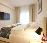 **SKVELÁ INVESTÍCIA**REZIDENCIA OPERA**KÚPELE TURČIANSKE TEPLICE** - Svetlá spálňa v 2-izbovom byte s TV, veľkou posteľou a nočným stolíkom.